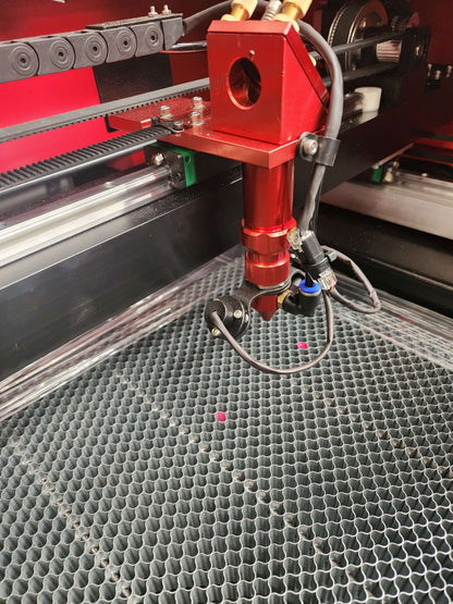 Close-up of the cutting head of the R960 Laser Machine 100W RECI W2 on a honeycomb bed.